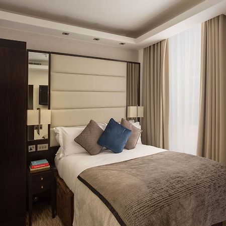 Hotel Montcalm Brewery Townhouse Londres Exterior foto The image shows a cozy bedroom. It features a comfortable double bed with a light-colored duvet and decorative pillows in shades of blue and gray. The headboard is upholstered in a soft material, and there are bedside lamps on either side of the bed.