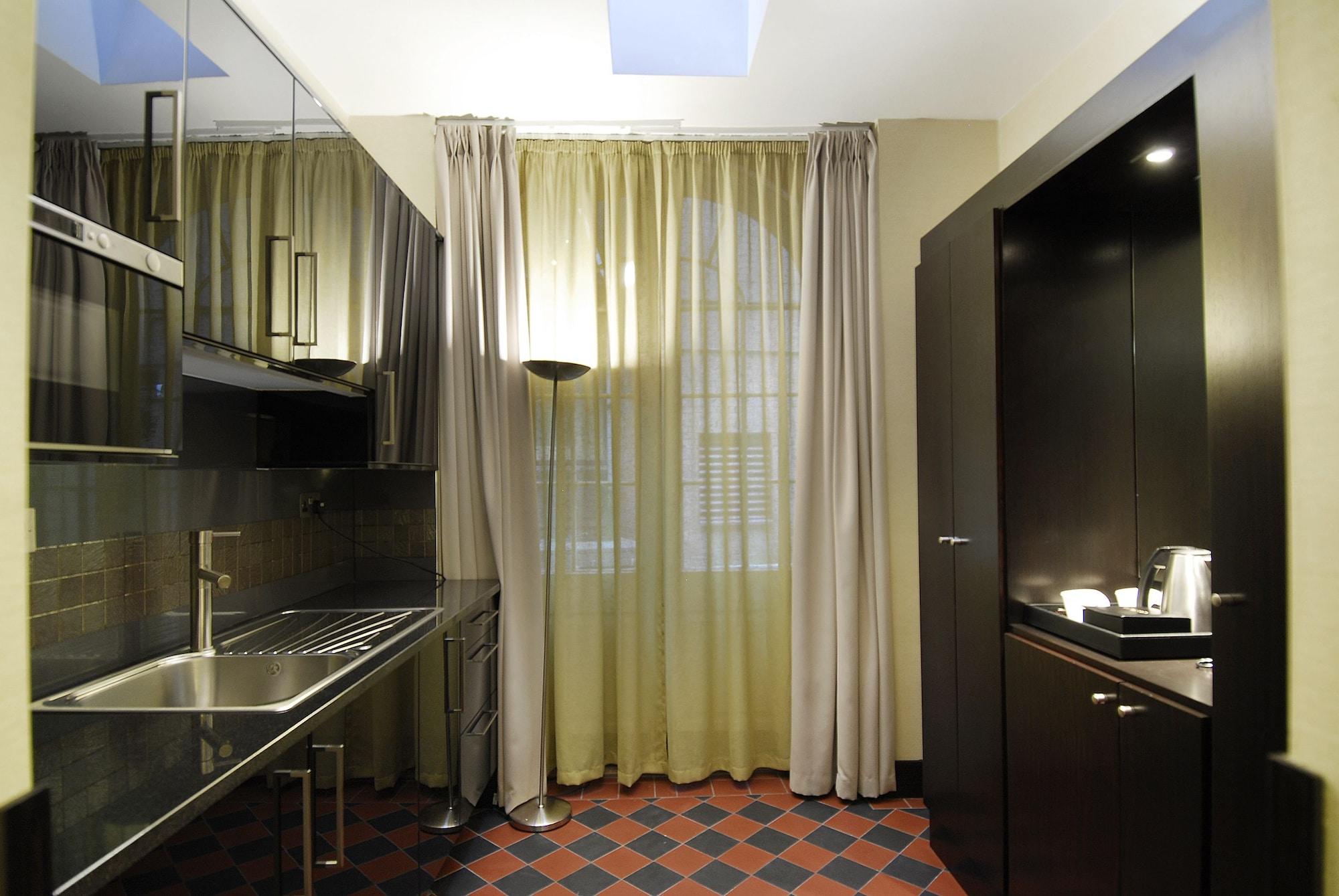 Hotel Montcalm Brewery Townhouse Londres Exterior foto The photo shows a modern kitchen space. On the left side, there is a sleek countertop and kitchen cabinets in a dark finish. The backsplash appears shiny, reflecting the surroundings. To the right, there is a tall black cabinet. A window is covered w