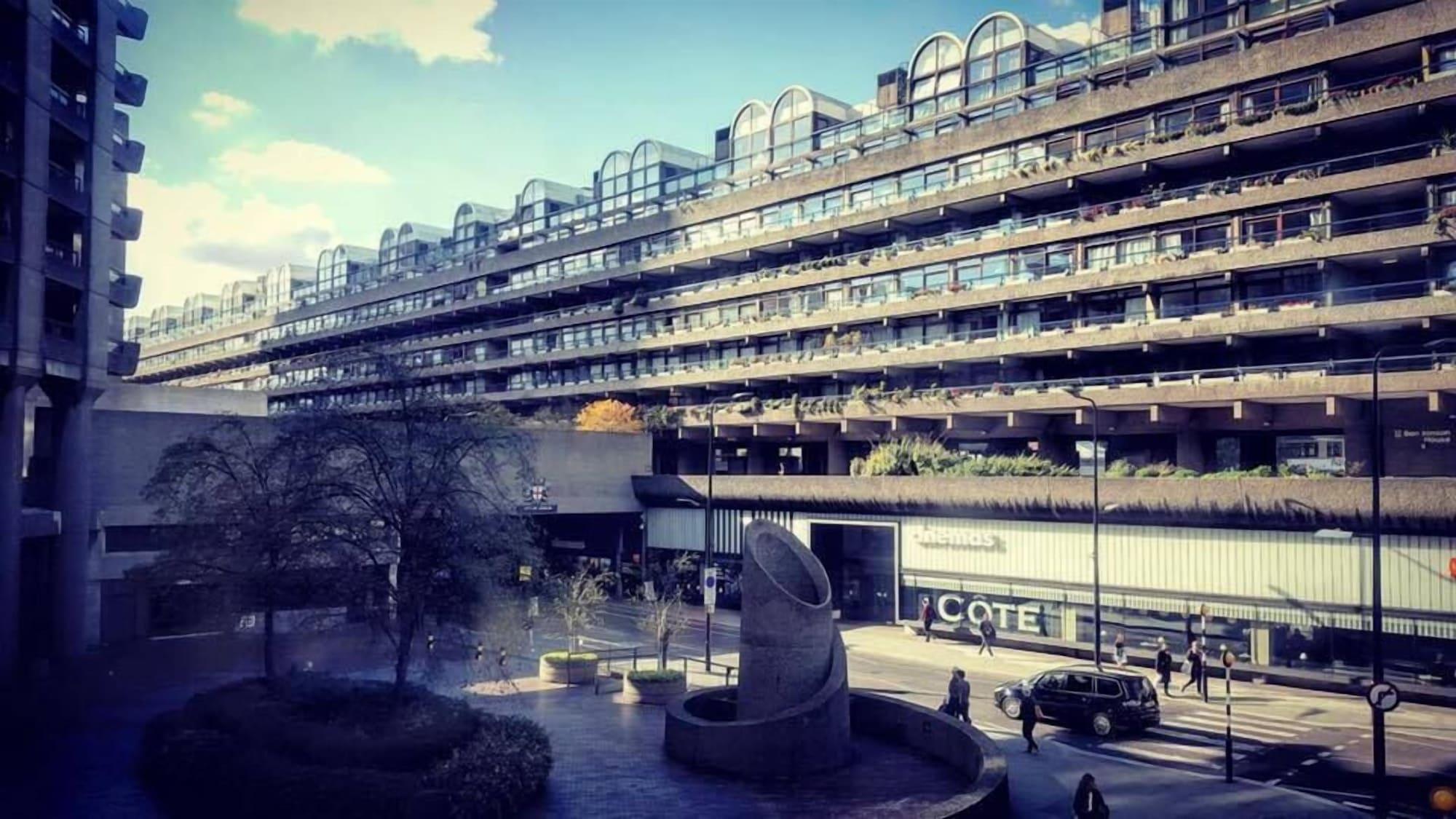 Hotel Montcalm Brewery Townhouse Londres Exterior foto The photo shows a modern architectural structure with multiple levels, featuring a series of large, rectangular balconies. Below this building, there is a plaza or courtyard area with a sculptural piece, which appears to be made of stone. Surrounding