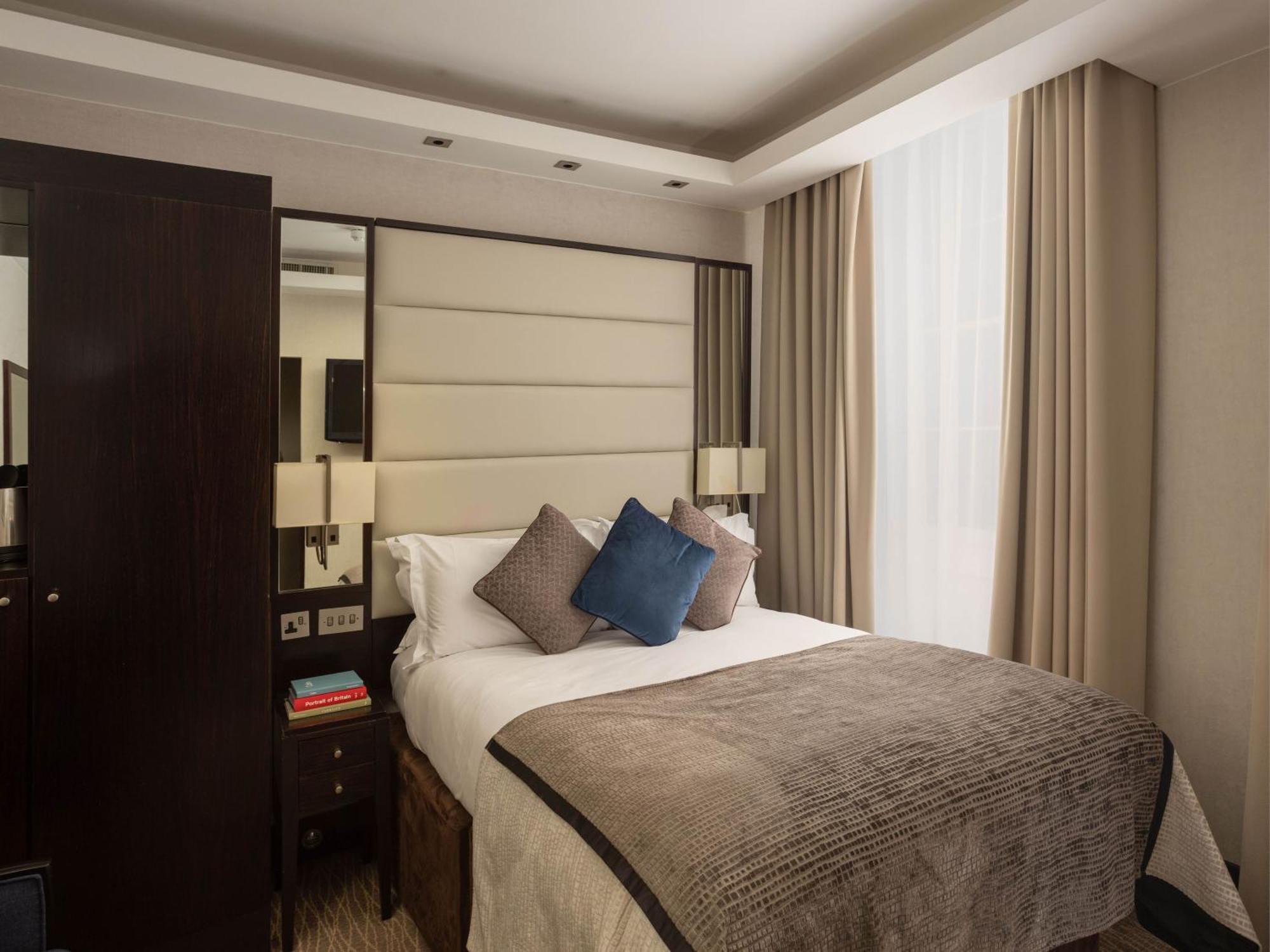 Hotel Montcalm Brewery Townhouse Londres Exterior foto The image shows a cozy bedroom. It features a comfortable double bed with a light-colored duvet and decorative pillows in shades of blue and gray. The headboard is upholstered in a soft material, and there are bedside lamps on either side of the bed.