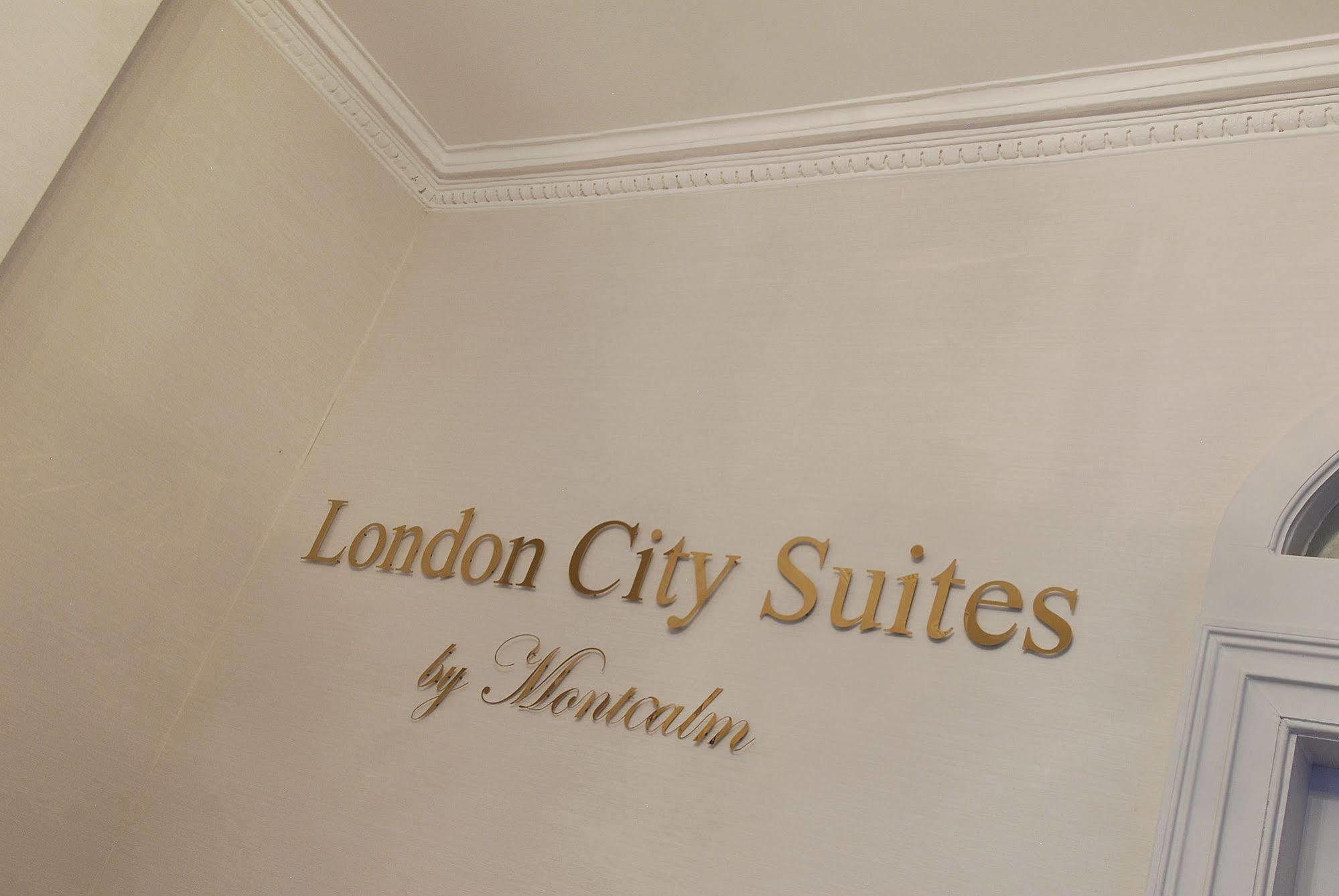Hotel Montcalm Brewery Townhouse Londres Exterior foto The photo shows a wall display featuring the text "London City Suites" in a bold, gold-colored font. Below that, the words "by Montcalm" are written in a smaller, elegant style. The background appears to be a neutral-colored wall, possibly in a hotel