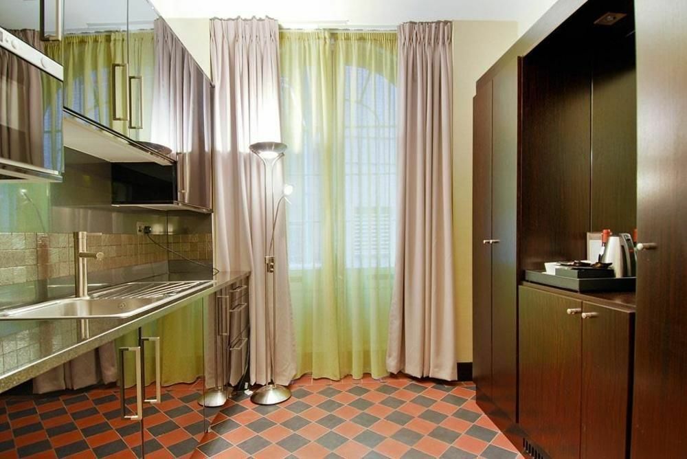 Hotel Montcalm Brewery Townhouse Londres Exterior foto The photo shows a modern kitchen area. There is metallic cabinetry and a stainless steel countertop with a sink. The walls are adorned with light-colored curtains that allow natural light to filter in, with one set in a soft purple hue and another in