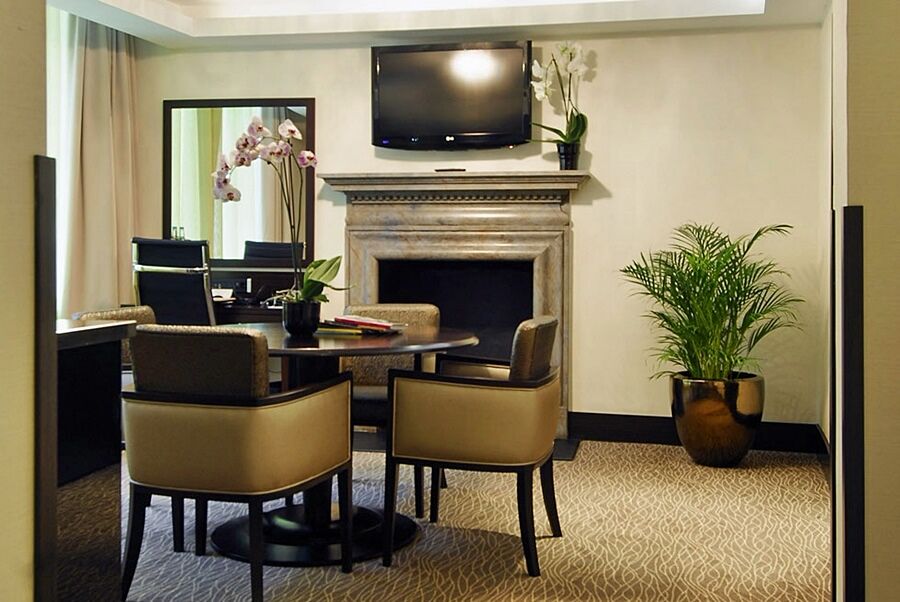 Hotel Montcalm Brewery Townhouse Londres Exterior foto The photo shows a modern and stylish room with a dining or meeting area. There is a round table surrounded by four upholstered chairs. A flat-screen television is mounted on the wall above a decorative fireplace. To the side, there is a mirror reflec