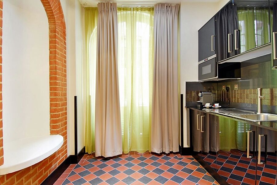 Hotel Montcalm Brewery Townhouse Londres Exterior foto The photo shows a kitchen area with modern design elements. There are large, light-colored curtains hanging from the windows, allowing natural light to filter in. The walls are partially exposed brick, giving a warm texture to the room. The flooring 