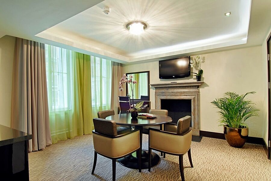 Hotel Montcalm Brewery Townhouse Londres Exterior foto The photo shows a well-furnished room, likely a hotel suite or a modern living space. It features a round dining table with four comfortable chairs. The walls are adorned with light-colored decor, and there are large windows with sheer and solid curt